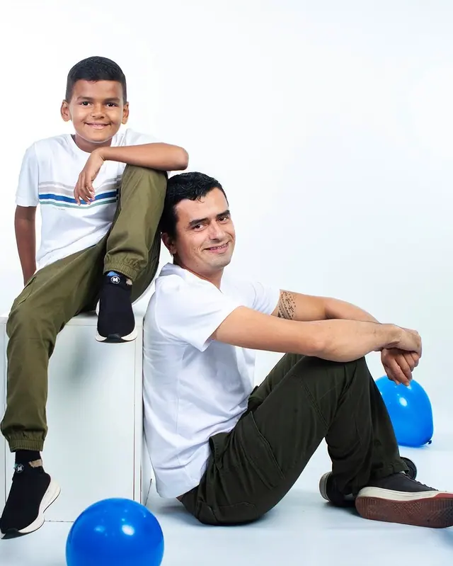 Pai e filho sentados em ensaio de estúdio com balões azuis