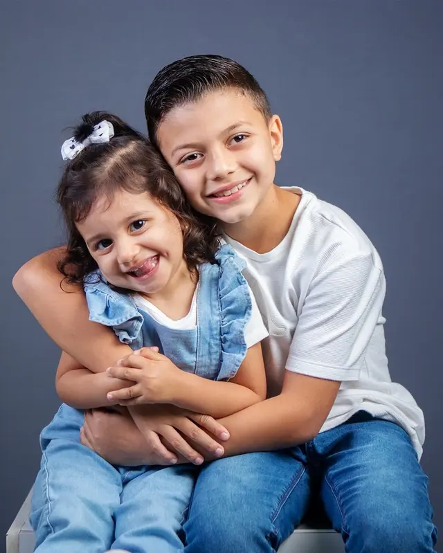 Irmãos abraçados e sorrindo em ensaio infantil