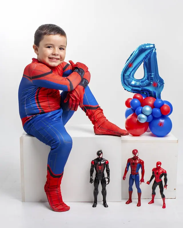 Menino fantasiado de herói com balão de número 4 em ensaio de aniversário
