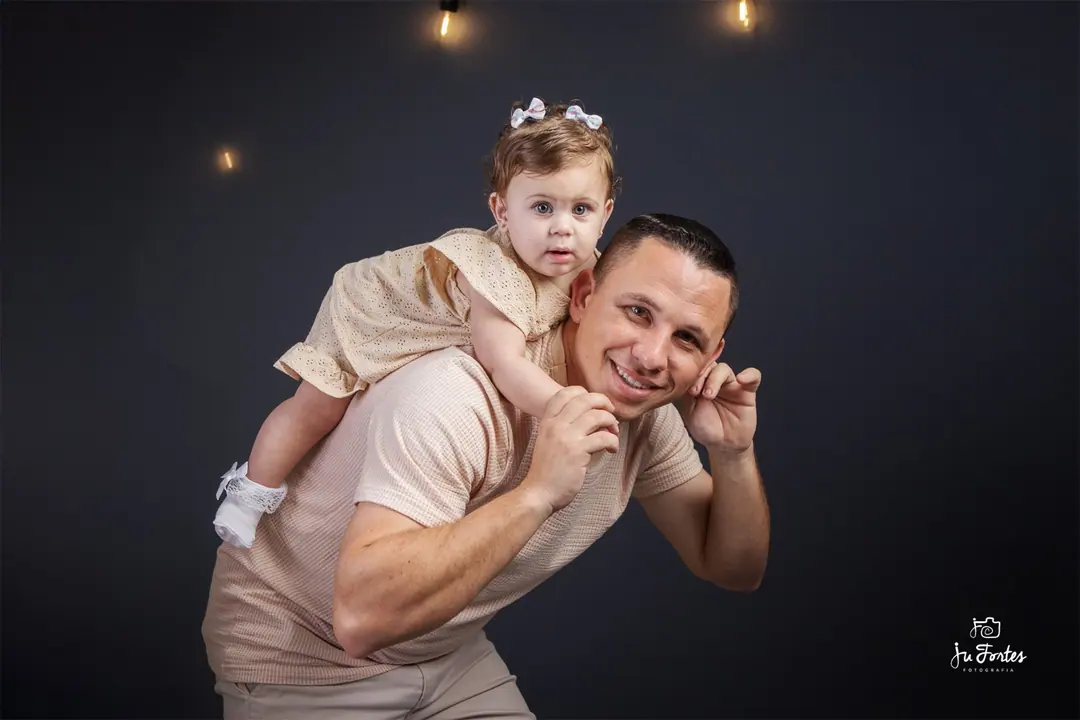 Pai com a filha nos ombros em ensaio de estúdio
